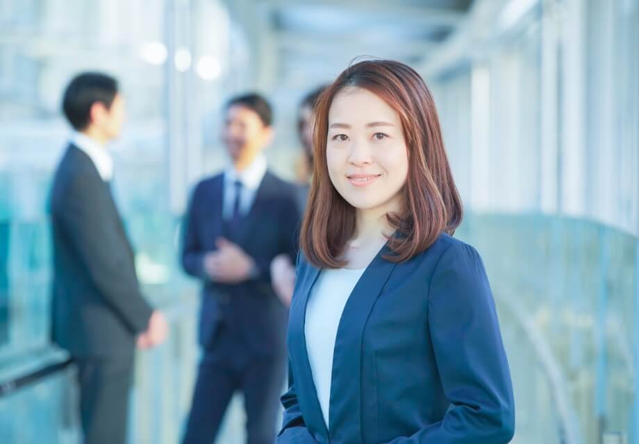 後ろで複数の弾性が話している様子と笑顔の女性