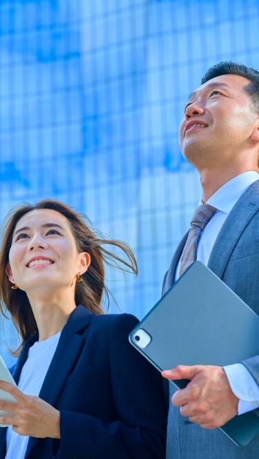 スマホを持った女性とダブレットを持った男性が空を見上げている様子